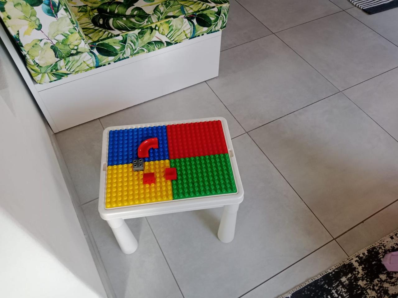 WhatsApp Image 2026-08-17 at 235033 - Margies Montessori Inspired Roodepoort White kid's table with a LEGO base plate divided into blue, red, yellow, and green sections and a few red bricks on top.